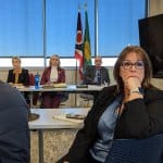 AMY PATTERSON/KMG Geauga Public Health Director of Nursing Carol Straniero watches as employees and the public react to an announcement during a special meeting March 15 that GPH will enter an agreement with the Lake County General Health District. The agreement includes laying off all current GPH employees effective March 31. GPH Board members Lynn Roman, left, Carol Brakey and Dr. Mark Rood look on in the background.