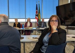 AMY PATTERSON/KMG Geauga Public Health Director of Nursing Carol Straniero watches as employees and the public react to an announcement during a special meeting March 15 that GPH will enter an agreement with the Lake County General Health District. The agreement includes laying off all current GPH employees effective March 31. GPH Board members Lynn Roman, left, Carol Brakey and Dr. Mark Rood look on in the background.